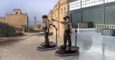 Two users wearing VR headsets train on Virtuix omni-directional treadmills inside a virtual battlefield environment.