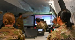U.S. Airmen inside a tactical operations center monitoring screens and coordinating command-and-control activities during a training exercise.
