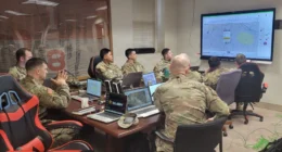 Soldiers in a command center monitor digital maps and data feeds during a multi-domain military training exercise.