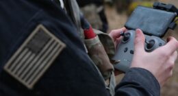 U.S. soldier controlling a drone with a handheld controller during a field training exercise.