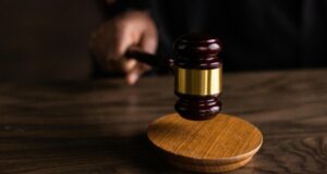 Close-up of a judge’s gavel striking a sound block during a courtroom proceeding.