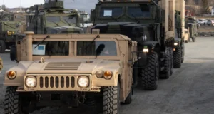 Humvee and military cargo trucks lined up in convoy at logistics site during ground operations