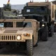 Humvee and military cargo trucks lined up in convoy at logistics site during ground operations