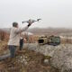 Operator deploying drone with AI edge processing system for real-time landmine detection in field environment