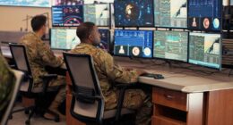US Air Force personnel in uniform analyzing multiple digital dashboards and data feeds inside a command and control center. USAF data strategy