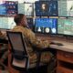 US Air Force personnel in uniform analyzing multiple digital dashboards and data feeds inside a command and control center. USAF data strategy