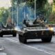 Ukrainian armored vehicles driving through a city street during military operations.