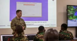 U.S. Army cyber specialist briefs Tanzania People’s Defence Force personnel during a cyber defense training session, with network security and cyber operations materials displayed on a projection screen in Dar es Salaam, Tanzania.